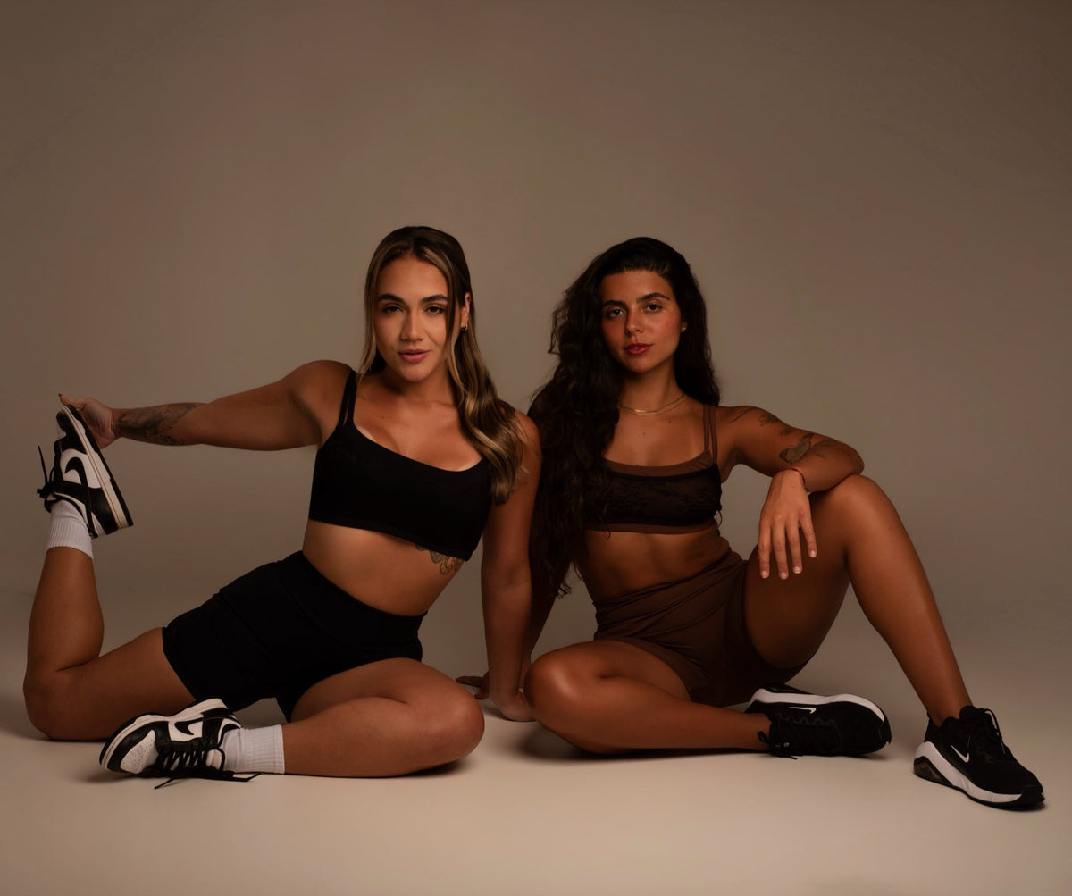 Duas modelos sentadas no estúdio com Top Renda Lyra e Short Siriús, em preto e marrom