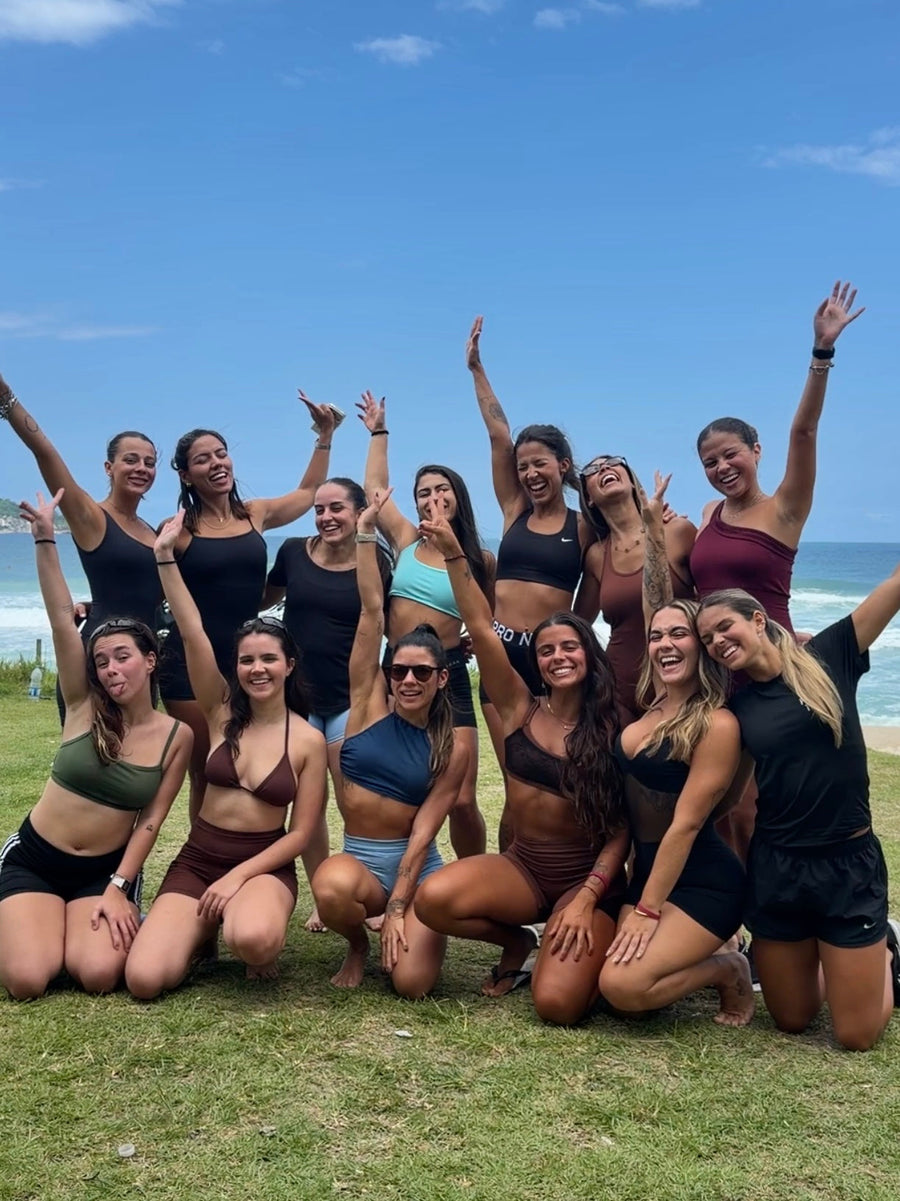Grupo de mulheres comemorando no gramado à beira-mar no lançamento da coleção Três Marias